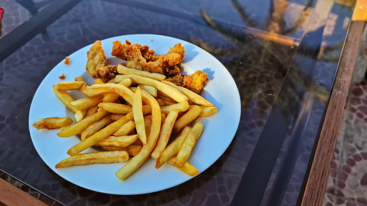 Shot of french fries served with chicken wings on white plate.