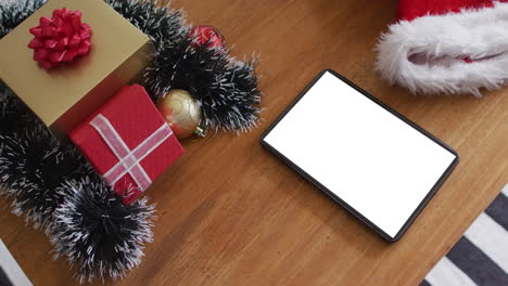 tableta con espacio de copia en la pantalla acostada en la mesa con sombreros de santa y regalos de navidad