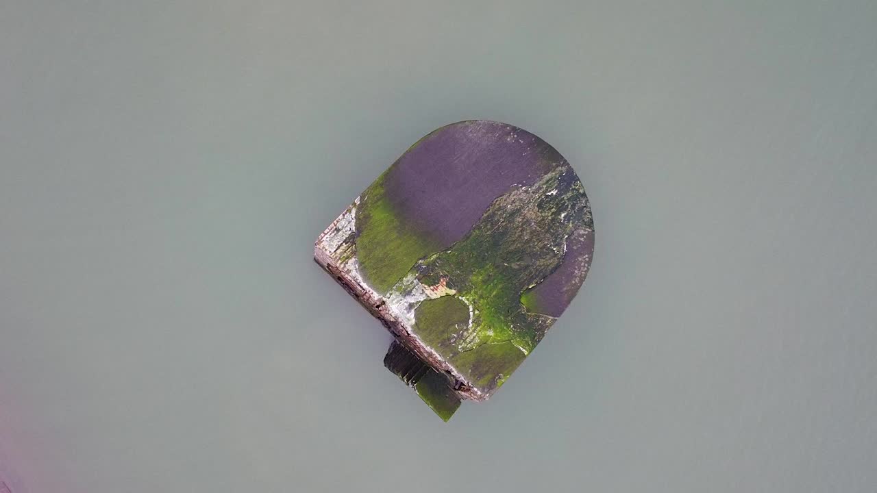 Aerial view of single abandoned seaside fortification bunker roof at Karosta Northern Forts on the beach of Baltic sea in Liepaja in overcast spring day, ascending drone shot revealing sea
