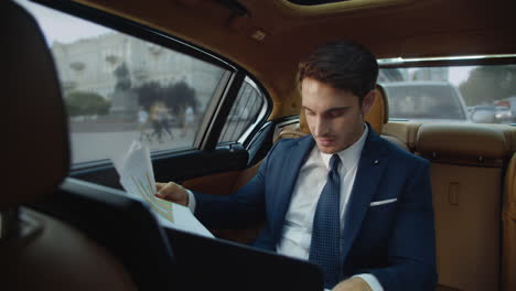 young male professional looking at data documents in business car. man in car