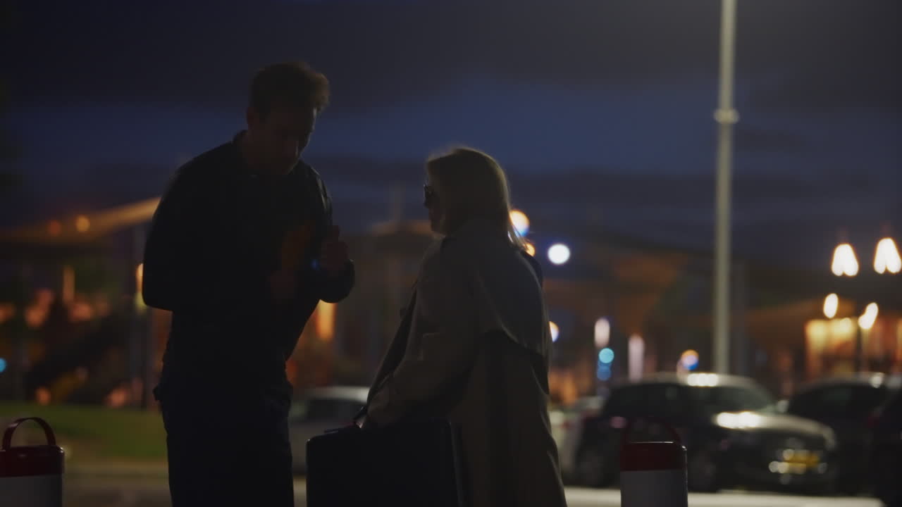 Secret late-night exchange between secret agents, man and woman in empty urban parking garage. Man hands over a large suitcase, receiving a folder in return. Confidential deal, crime, or espionage