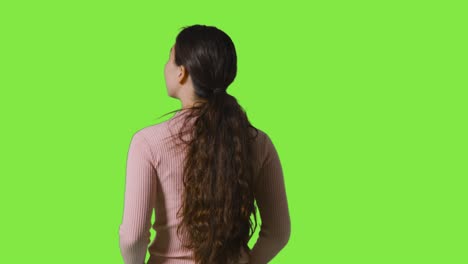 rear view studio shot of woman looking all around frame against green screen in vr environment 1