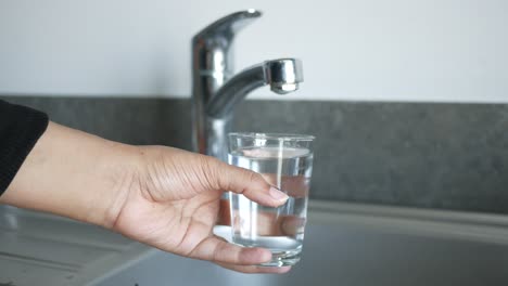 hand holding a glass of water from a kitchen tap