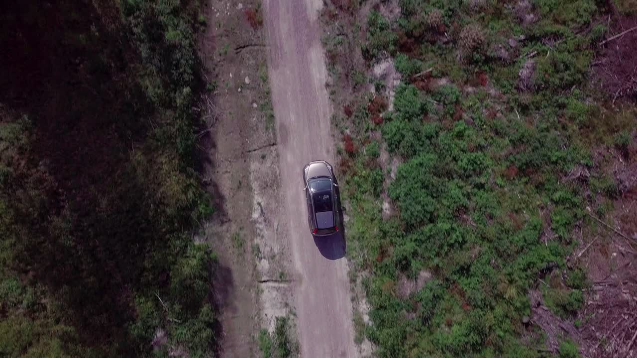 Vista aerea dall'alto di un'auto generica che guida su una strada sterrata rurale.