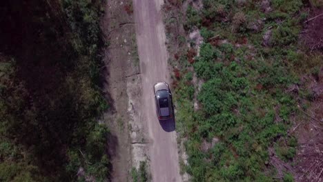 Top-down-aerial-view-of-generic-car-driving-on-rural-gravel-road