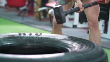 girl beats with a hammer in training a strong woman punches a tire athletic muscular girl beats with a hammer in training