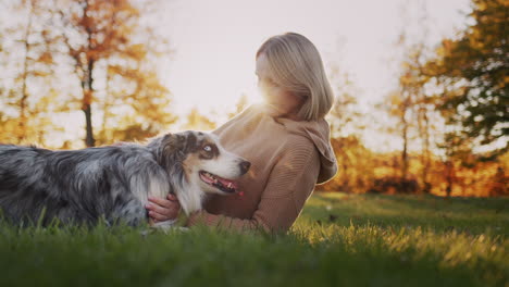 a young woman is resting in a park, next to her is her dog. the setting sun illuminates them