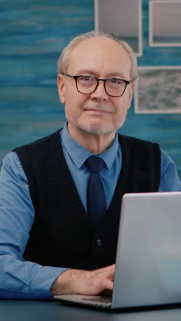 vertical video: retired manager sitting at desk in front of camera smiling