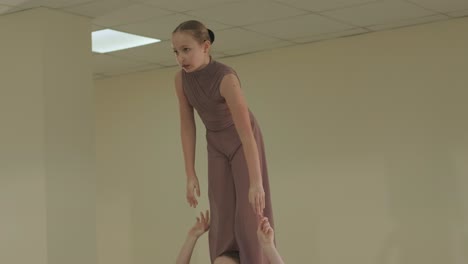 a group of young ballet students in black dancewear practicing positions in a spacious ballet studio with wooden flooring and wall-mounted barres. focused expressions and synchronized movements.