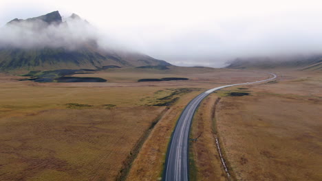 aerial pan up foggy road to vik iceland early winter at black sand beach apostles fire and ice ocean next to dyhrolaey lighthouse and cave reynisfjara