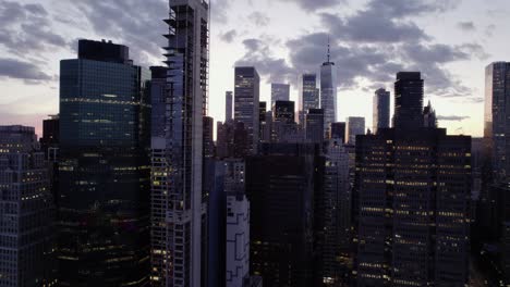 Flying-in-middle-of-illuminated-skyscrapers,-in-New-York,-USA---Aerial-pull-back