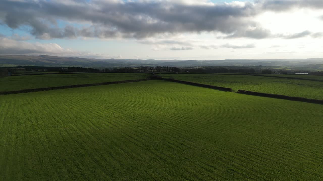 Aerial reverse flight showcasing lush farmland, roads, and distant hills.