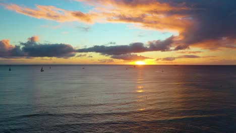 tropical hawaiian sunrise over boats sailing across colorful sea near waikiki beach in honolulu, hawaii