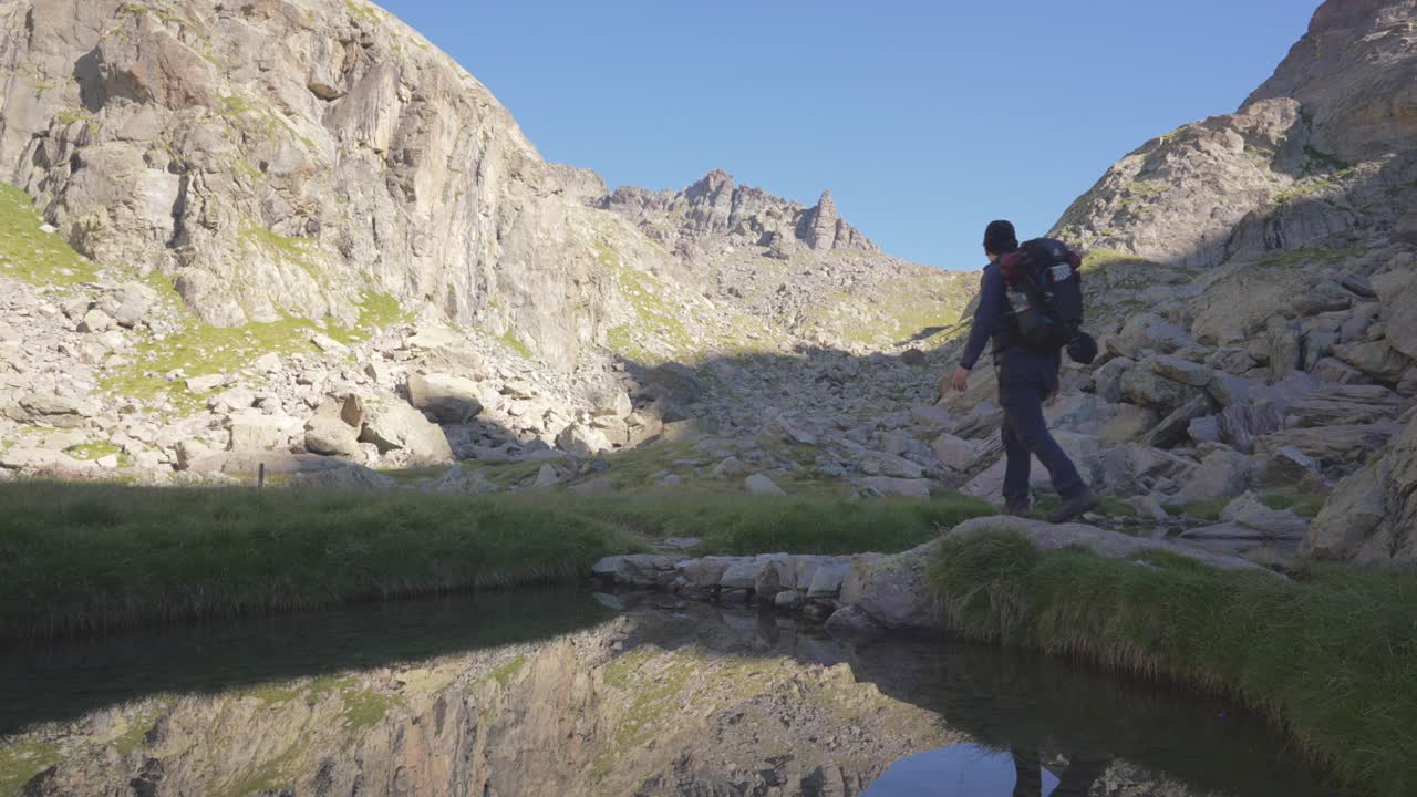 un hombre caminando por las montañas, pasa un lago, el reflejo en el agua