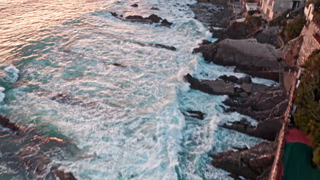 Las-Olas-Chocan-Contra-La-Costa-Rocosa-Y-Escarpada-De-Baccadasse-Génova-Durante-La-Puesta-De-Sol,-Drones