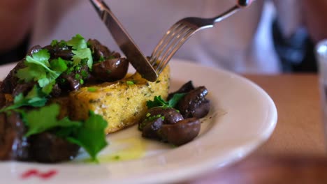 close up in slow motion, cutting hash brown with knife and fork on a fancy dish in a cafe