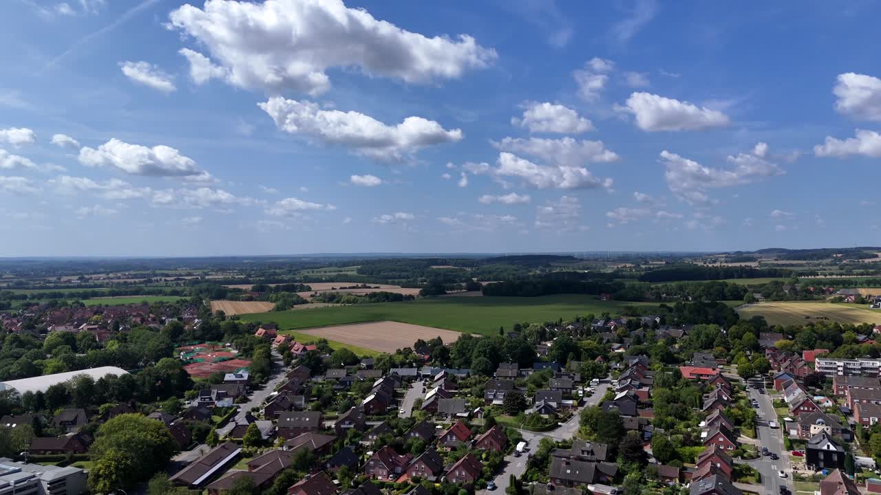 White clouds at blue sky over city in America. Neighborhood with brick houses and rural fields in distance. Wisconsin, United States. Peaceful landscape in nature. Aerial wide shot