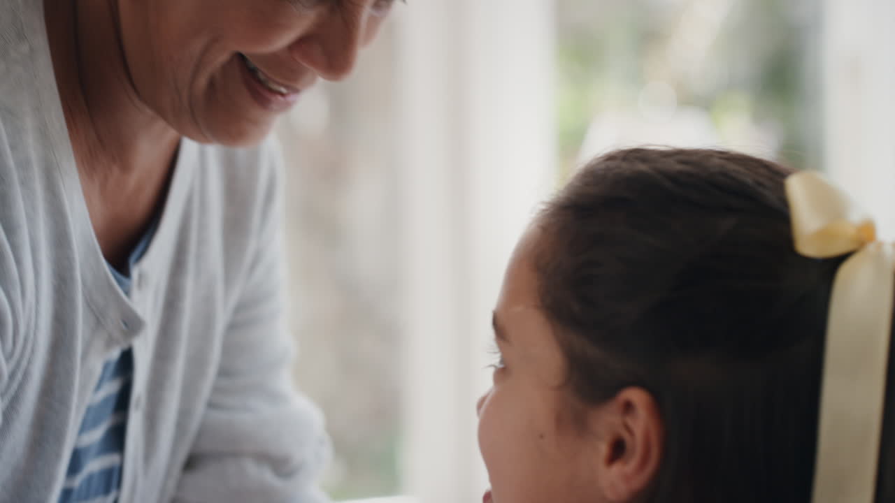 할머니가 작은 소녀를 이마에 부드럽게 키스하고 손녀에 대한 사랑을 보여주고 자랑스러운 할머니는 손녀에 대한 사랑을 느끼고 있습니다.