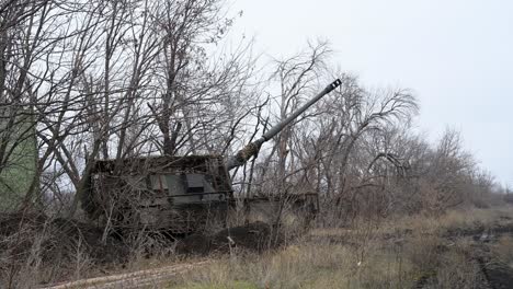 a german-made pzh 2000 howitzer in a camouflaged firing position in ukraine, its long cannon elevated towards the russian front. a scene from the artillery duels of the war