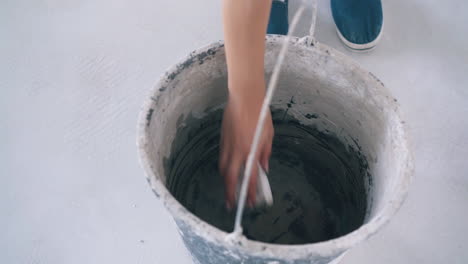 woman wets little rag with water in bucket on floor closeup