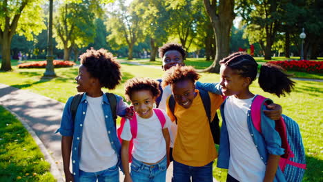 joyful group of young friends with backpacks in a sunny park