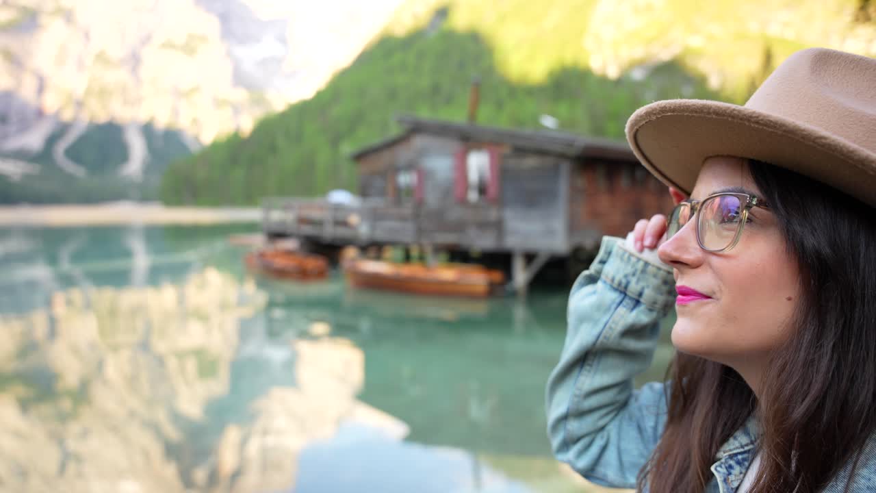 hermosa mujer blanca con sombrero admirando lago di braies durante el día