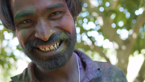 indian man close-up of face smeared with bright holi colors