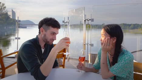 happy young couple drinking wine on a river dock at sunset