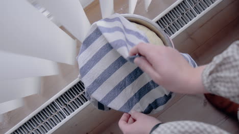mujer joven revisando la masa levantada en el calentador para un pastel en la cocina en casa