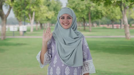 happy muslim woman saying hello in park