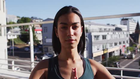 Portrait-of-mixed-race-gender-fluid-person-practicing-yoga-meditation-on-roof-terrace