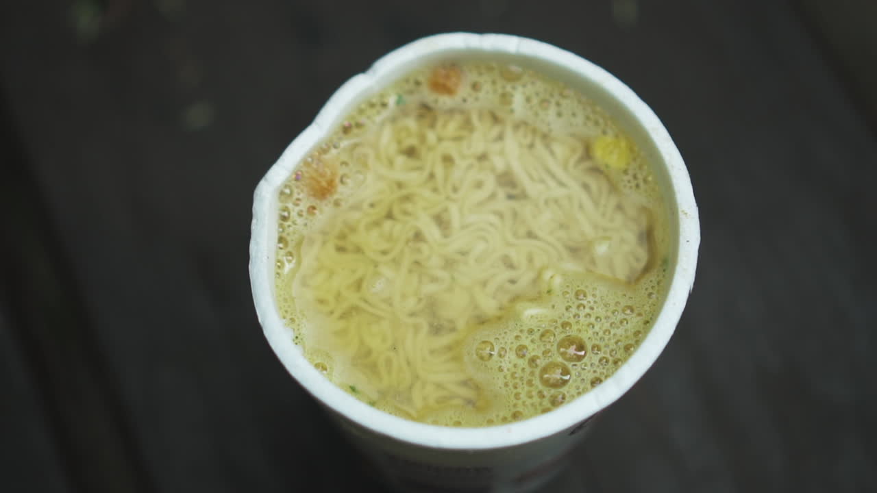 vista superior de fideos instantáneos en taza con agua hirviendo