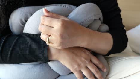 woman hugging a knotted grey pillow
