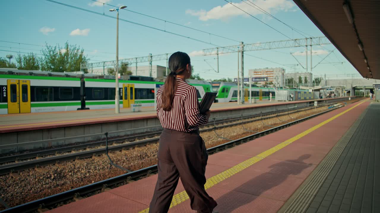 Nainen odottaa junaa asemalla