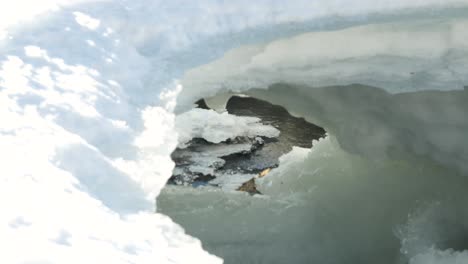 Small-creek-surrounded-by-snow-and-ice,-shot-on-tripod-in-the-northern-sweden