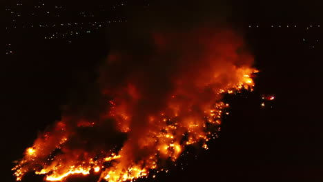 aerial view towards a glowing red field on fire, australian wildfires, during night time, in queensland, australia - dolly, drone shot