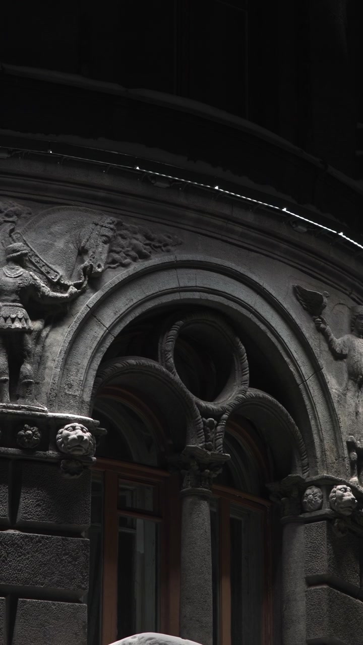 Facciata in pietra ornata di notte. Primo piano che mostra rilievi classici intagliati illuminati da una fredda illuminazione architettonica