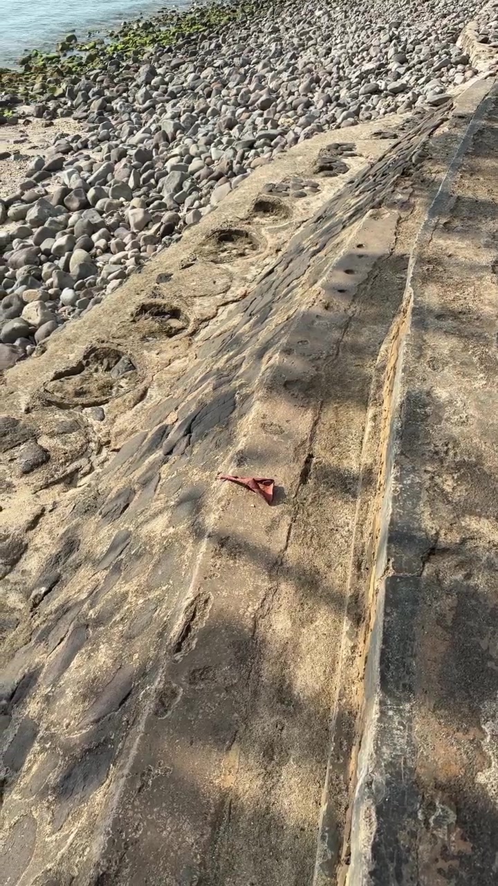 Muraglione in cemento e litorale roccioso.