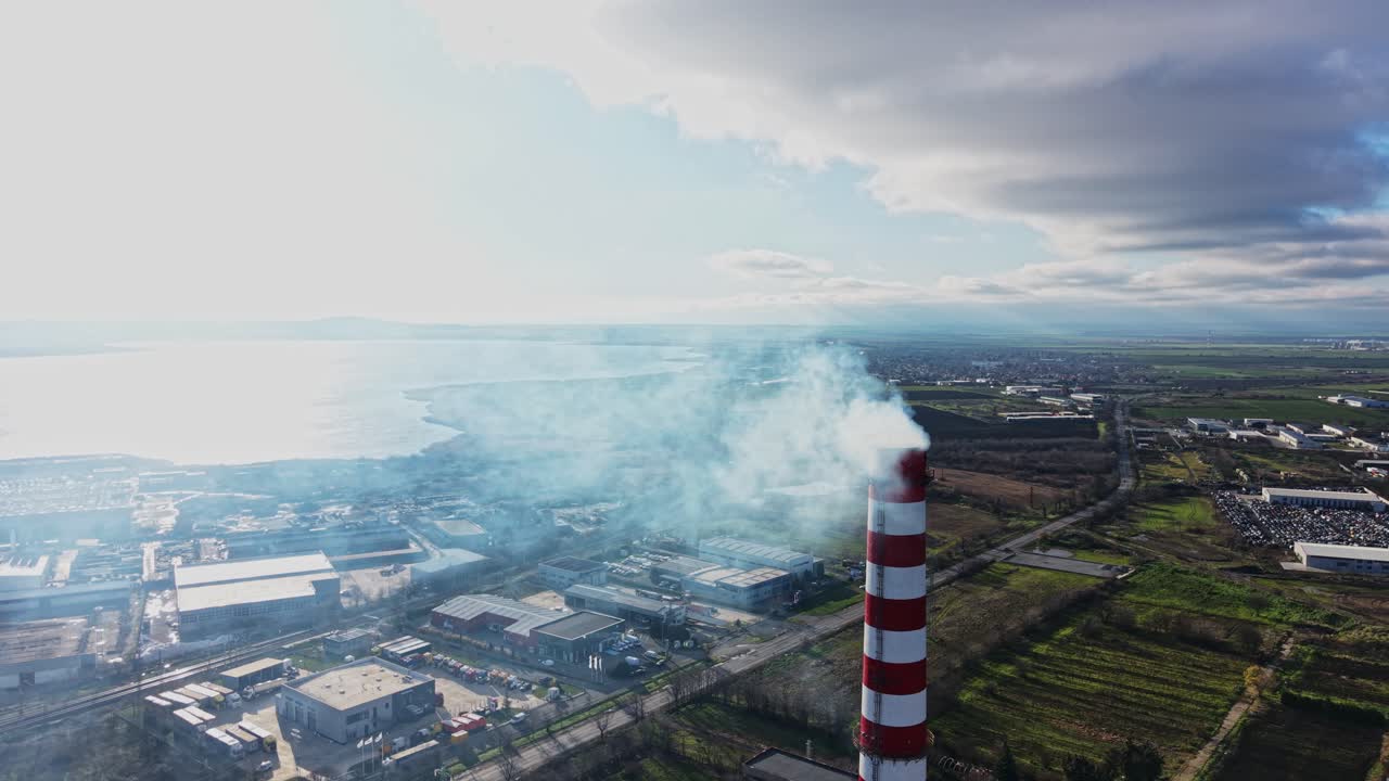 Grande camino industriale rilascia fumo sull'acqua e sulla terraferma
