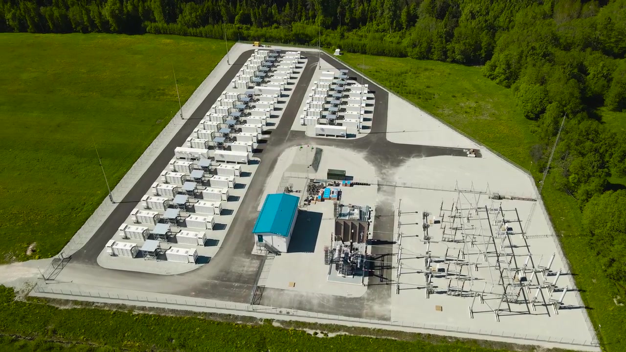 Aerial view of a renewable energy battery storage facility with modern container units and an electrical substation, storing power for a stable and sustainable electricity supply grid