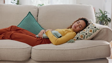 woman in pain lying on couch holding her stomach