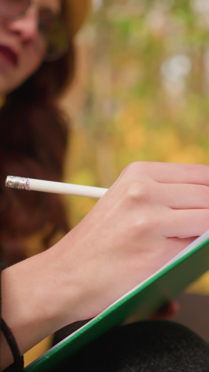 Close up of creative mind sketching thoughtfully on canvas with blurred autumn leaves in background, focus on artistic expression, pencil strokes, and deep concentration in a serene outdoor setting