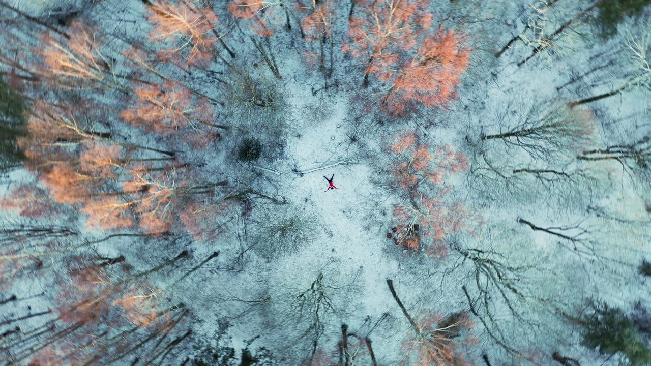 Persona con cappotto rosso sdraiata sulla neve durante l'inverno nel Parco Ekeberg, Oslo, Norvegia