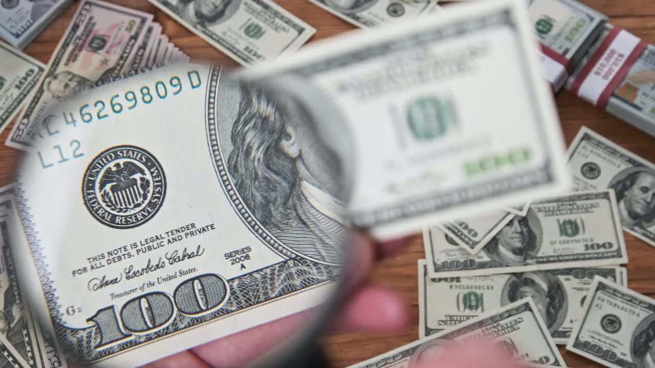 cien dólares inspeccionando bajo lupa en el fondo del dinero
