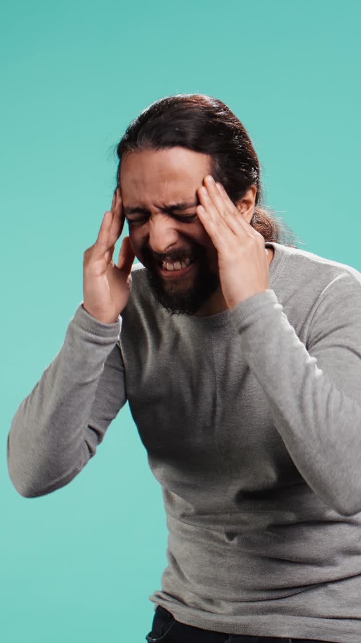 Vertical video Portrait of man feeling exhausted from overworking, suffering from headache