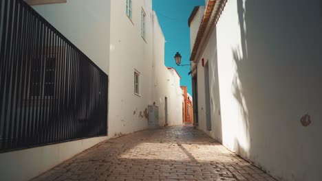 portugal algarve loule calle estrecha de piedra vacía con sombra de árboles, linterna pública al sol de la mañana 4k