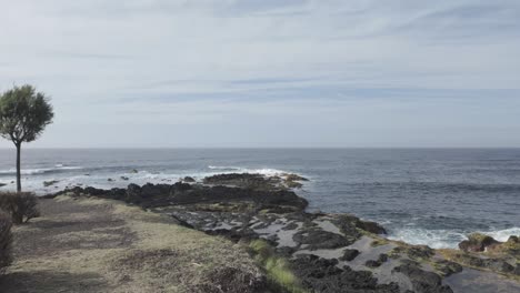 wide shot of mosteiros, sao miguel coast with rough seas and rocky shoreline under a cloudy sky, natural colors, daytime