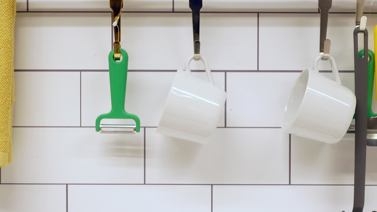 cocina con azulejos blancos y utensilios de cocina colgando de ganchos