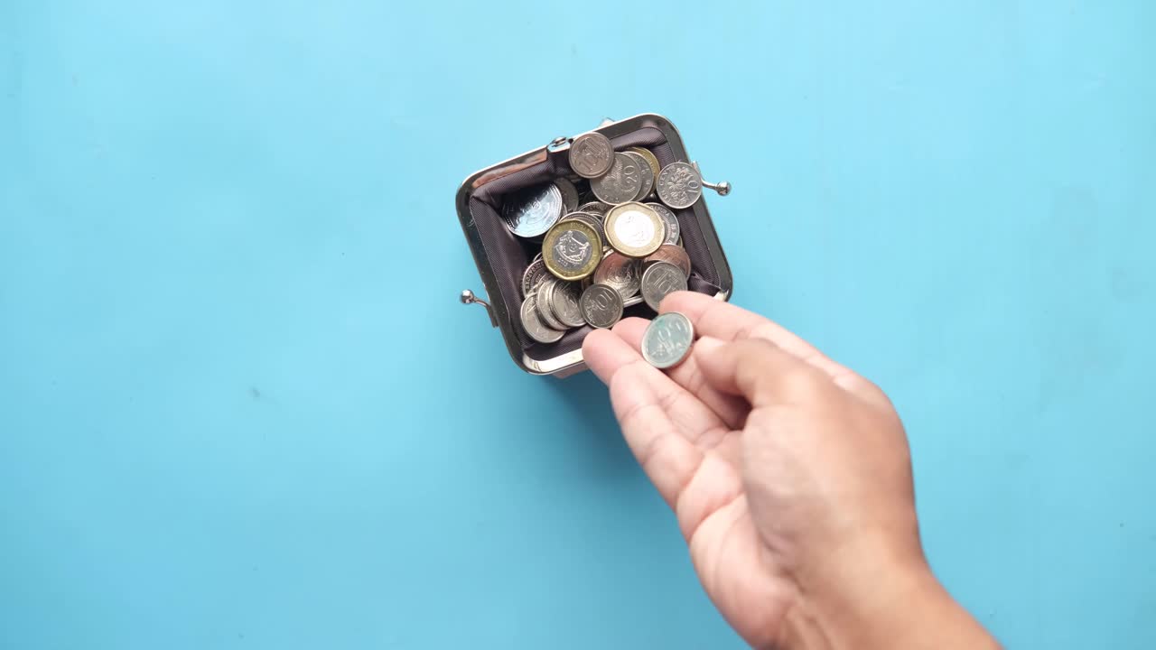 vaciando a mano las monedas de una pequeña billetera