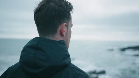 caucasian man standing at the shore and looking into the distance